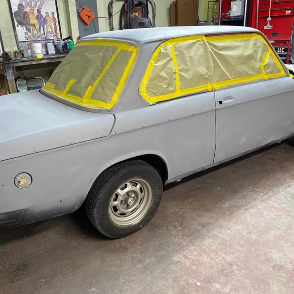 Classic BMW 2002 in primer being prepped for paint inside the iRestore Auto Body shop